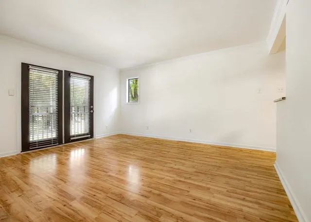 a view of an empty room with glass door and wooden floor