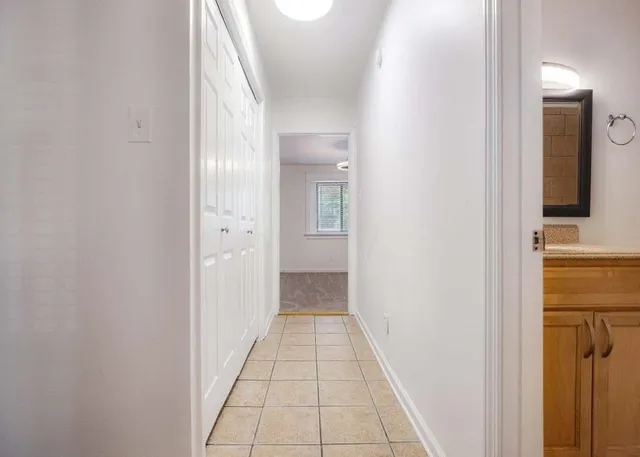 a view of a hallway with wooden floor and a bathroom