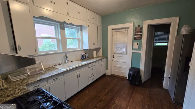 a kitchen with granite countertop a refrigerator a sink and wooden floors