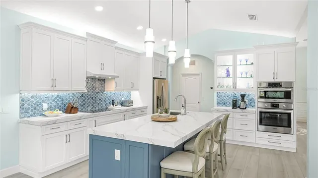 a kitchen with stainless steel appliances kitchen island granite countertop a table chairs in it and white cabinets
