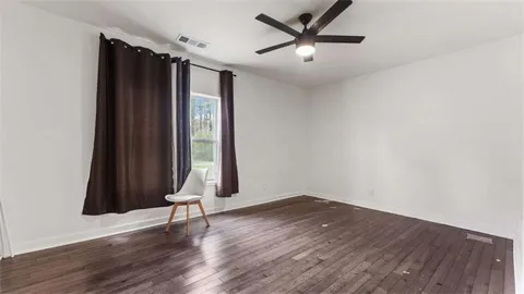 a view of empty room with wooden floor and window