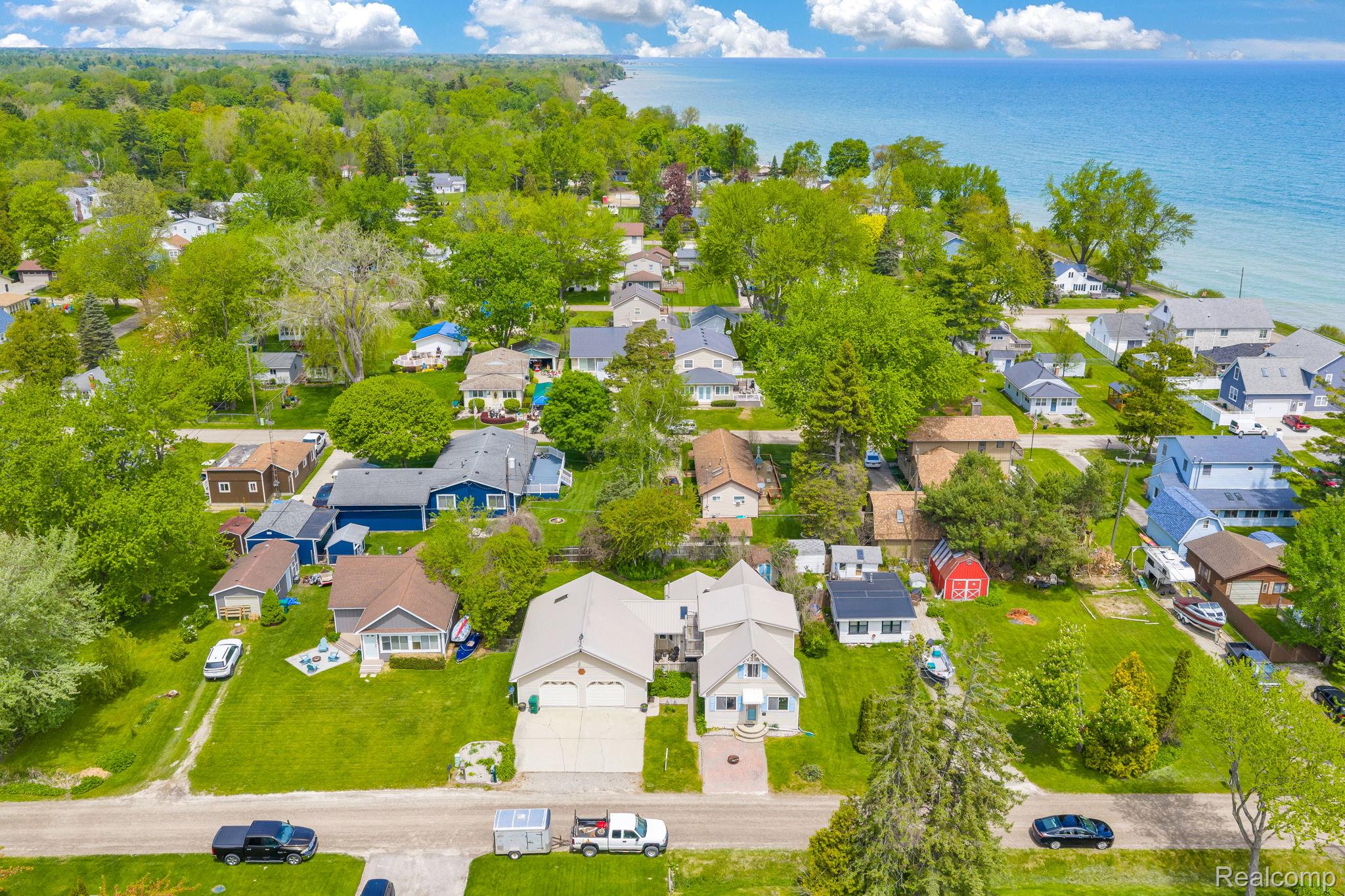 7489 Aspen Road Lexington, MI 48450 - Photo 4 of 62 Aerial perspective showcasing a residential neighborhood with verdant trees and manicured lawns