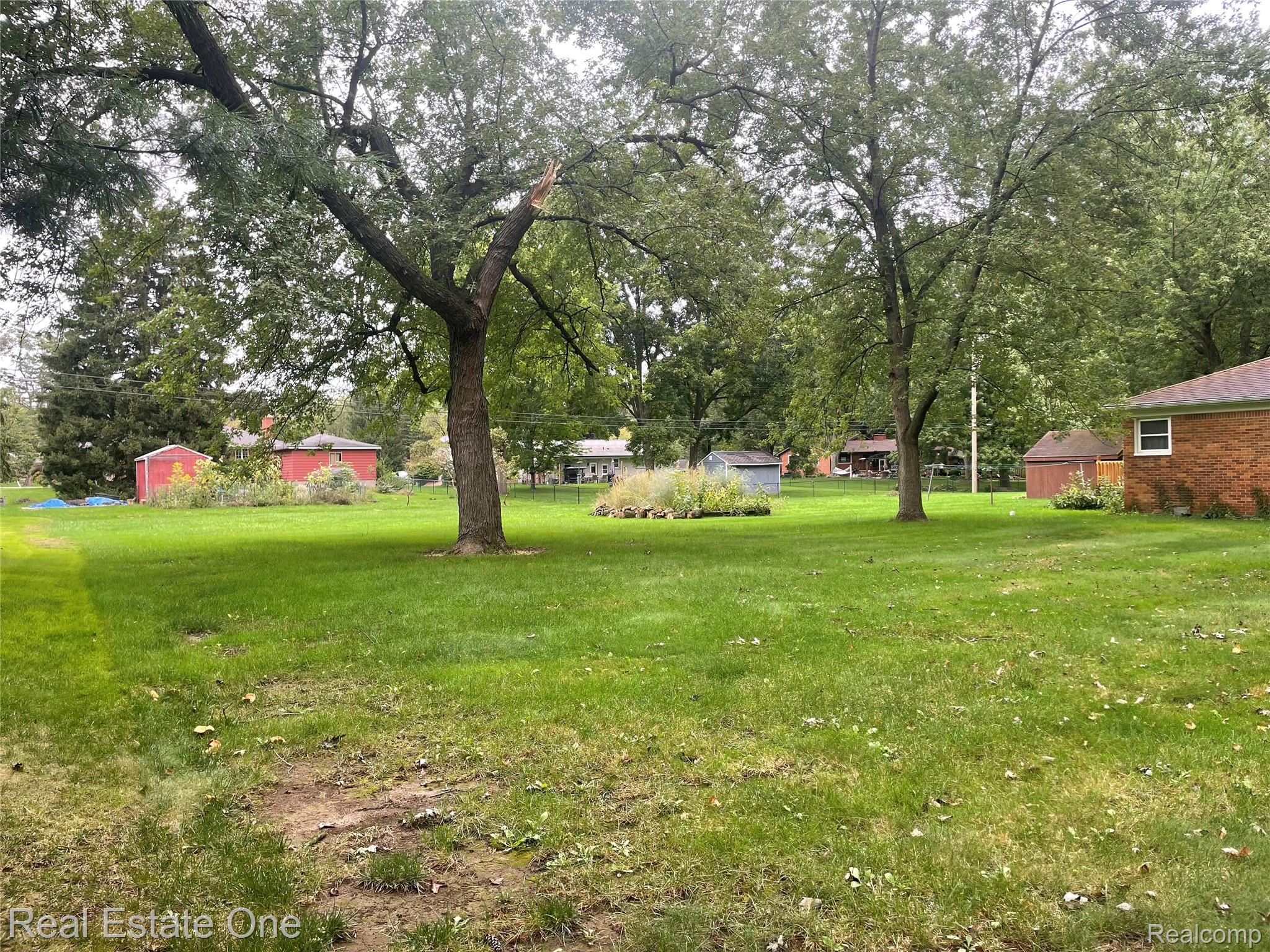 6346 Donaldson Road Troy, MI 48085 - Photo 7 of 8 Expansive green lawn with mature trees and a brick-sided structure