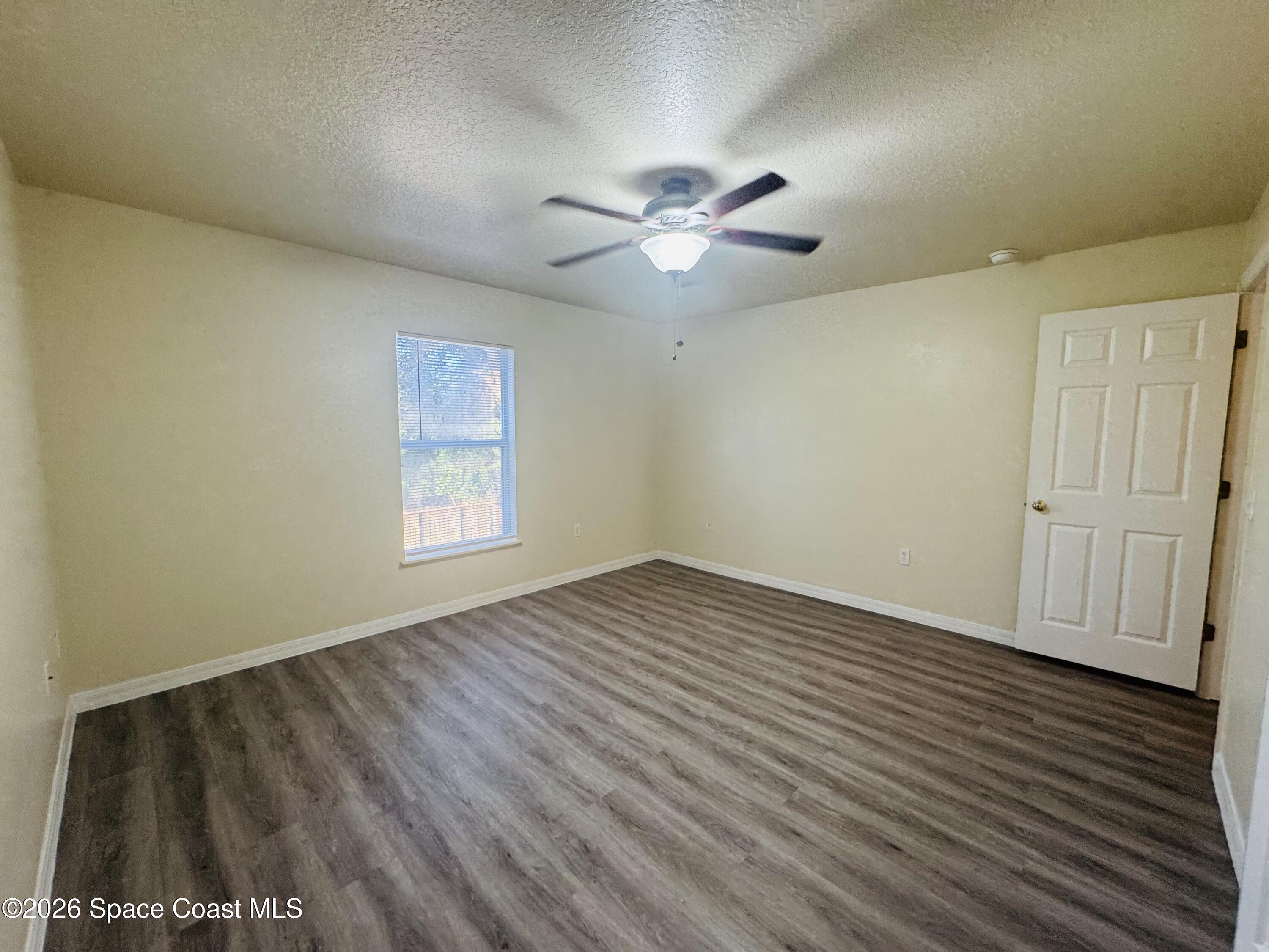 4550 Elena Way Melbourne, FL 32934 - Photo 11 of 33 a view of an empty room with wooden floor and a window