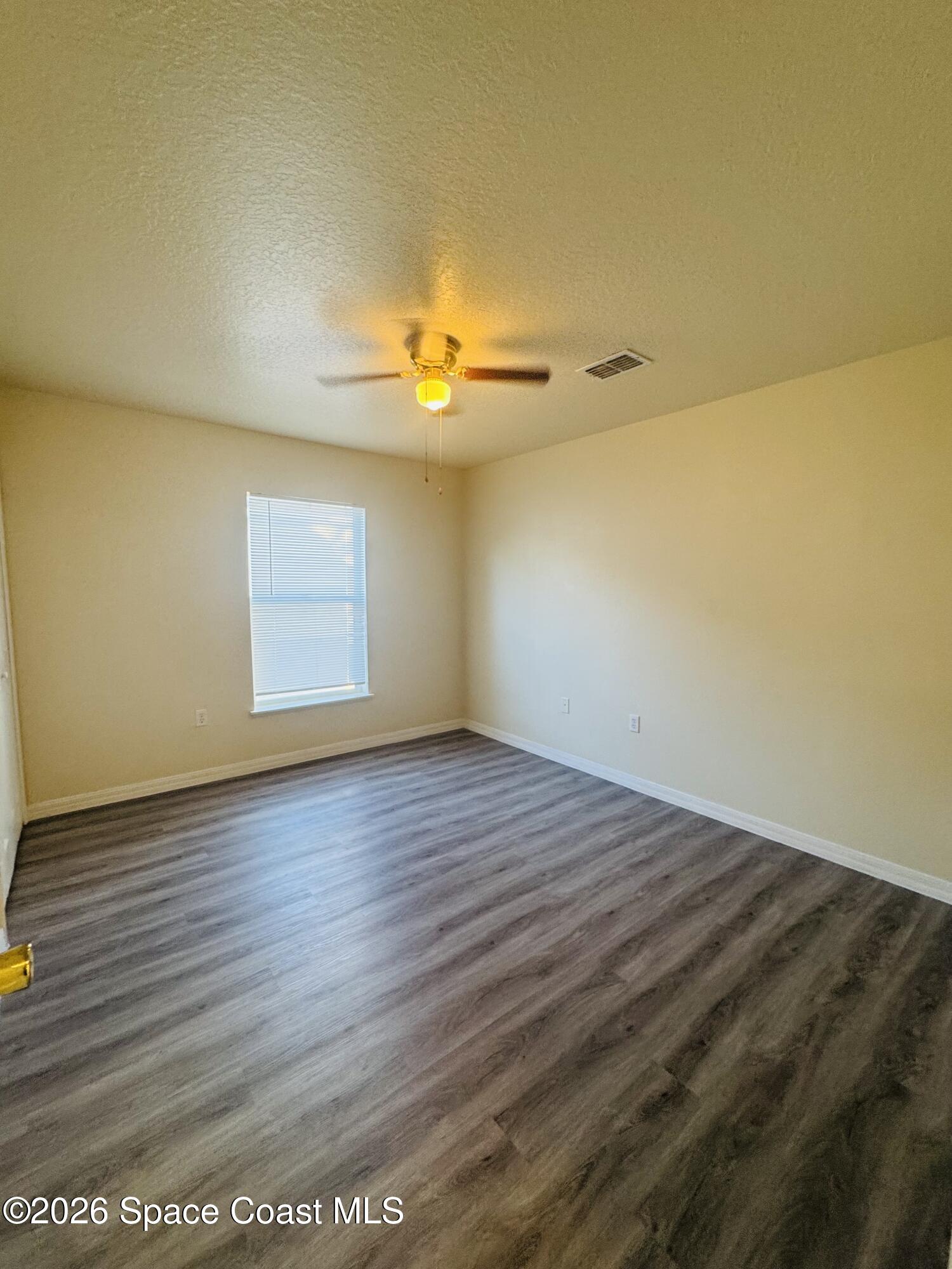 4550 Elena Way Melbourne, FL 32934 - Photo 12 of 33 an empty room with a wooden floor and a window