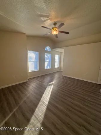 a view of empty room with wooden floor and fan