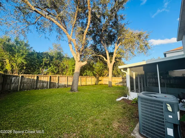 a backyard of a house with plants and large tree