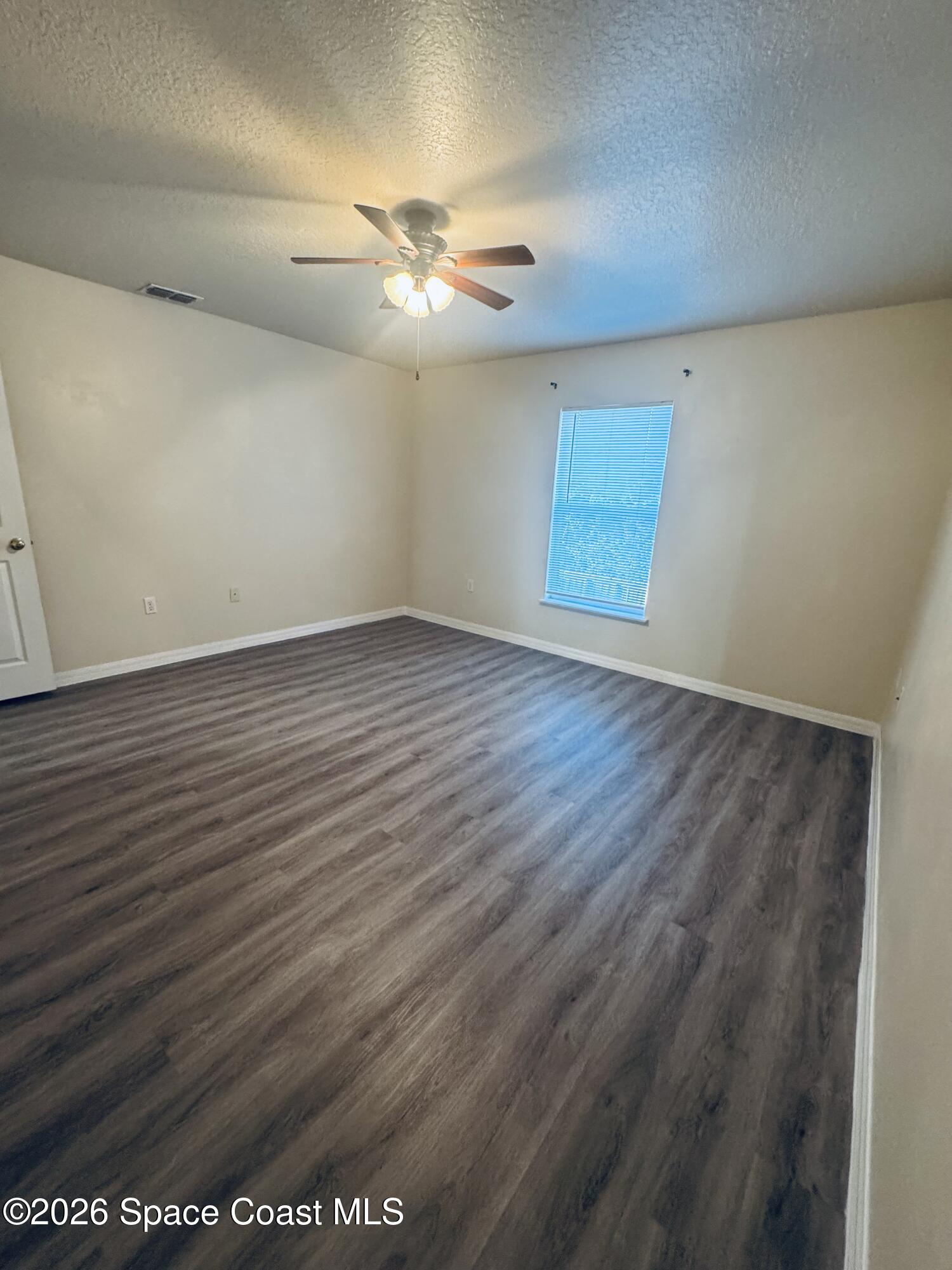 4550 Elena Way Melbourne, FL 32934 - Photo 10 of 33 an empty room with wooden floor fan and windows