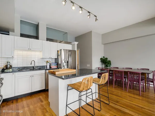 a kitchen with stainless steel appliances granite countertop a table chairs sink and cabinets