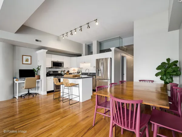 a kitchen with stainless steel appliances kitchen island granite countertop a stove a refrigerator a kitchen island a dining table and chairs with wooden floor
