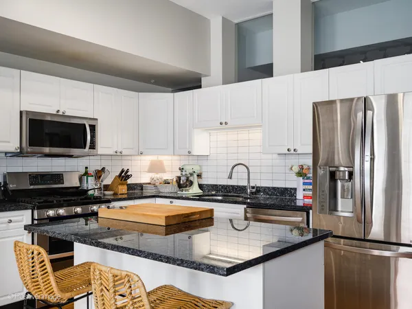 a kitchen with stainless steel appliances granite countertop a sink refrigerator and microwave