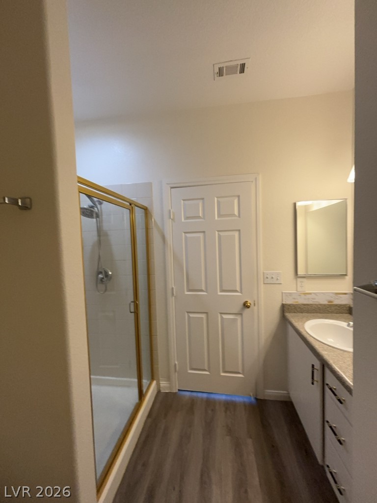 4915 East Russell Road, Unit 154 Las Vegas, NV 89120 - Photo 10 of 20 Plank flooring runs past a modern vanity to a glass-enclosed walk-in shower.