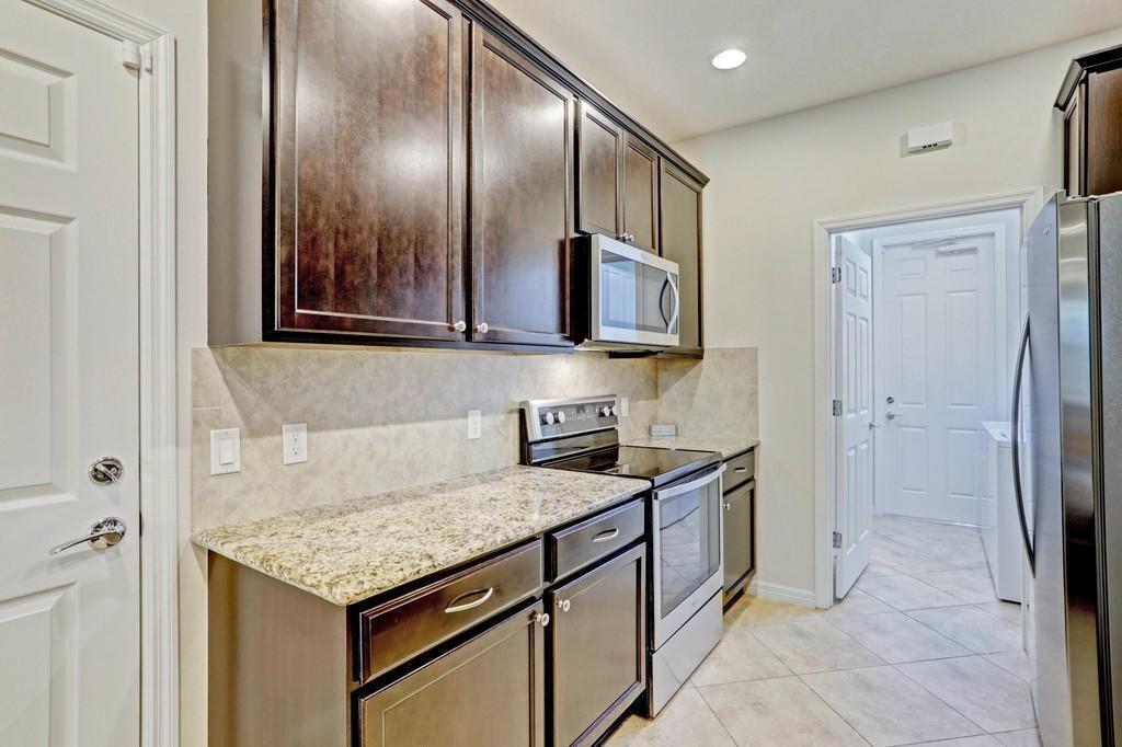 1132 South Community Drive Jupiter, FL 33458 - Photo 5 of 20 a kitchen with stainless steel appliances granite countertop a sink and a refrigerator