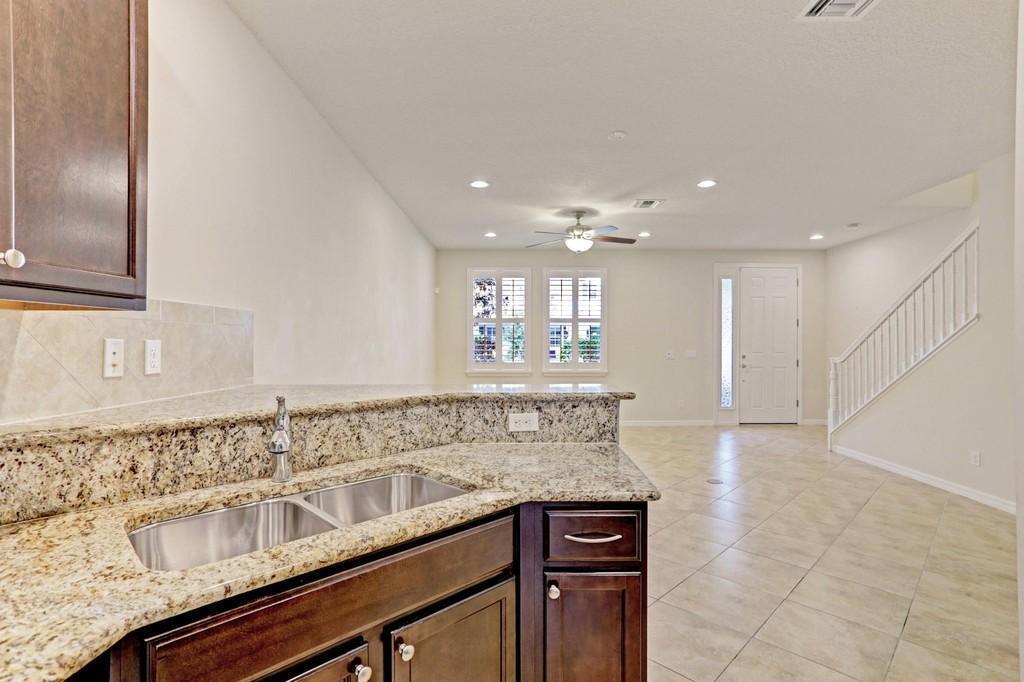 1132 South Community Drive Jupiter, FL 33458 - Photo 6 of 20 a view of a kitchen counter top space with stainless steel appliances granite countertop a sink and a wooden floor