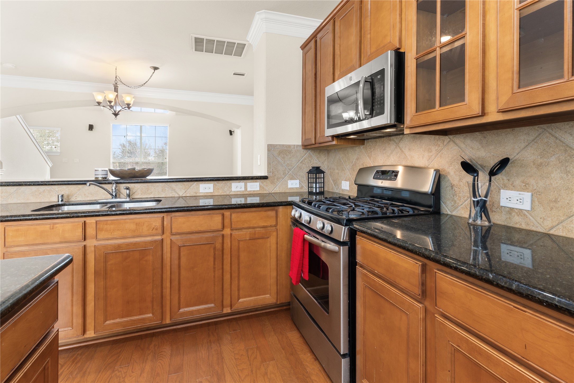 3334 Clearview Villa Way Houston, TX 77025 - Photo 11 of 35 Modern kitchen with stainless steel appliances, granite countertops, and wooden cabinets. Open layout with a view into a bright, spacious living area. Enjoy cooking on the gas range.
