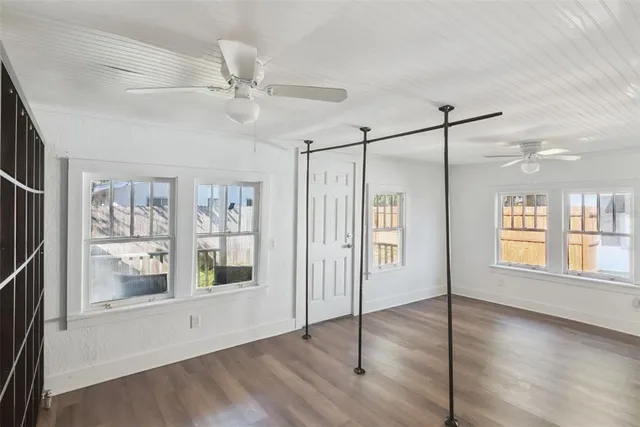 a view of an empty room with window and wooden floor
