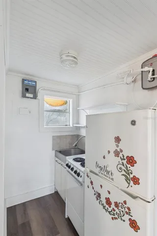 a kitchen with a stove a refrigerator and wooden floor