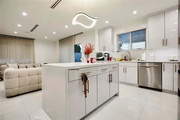 a kitchen that has a lot of white cabinets and couches with wooden floor