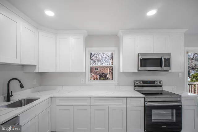 a kitchen with stainless steel appliances granite countertop a sink a stove a microwave a refrigerator and cabinets