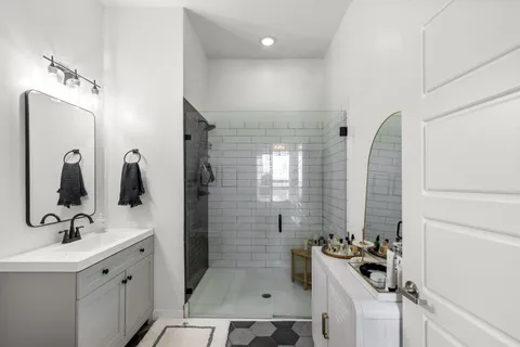 a bathroom with a double vanity sink a mirror a window and a shower