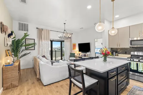 a living room with stainless steel appliances kitchen island granite countertop furniture a fireplace a flat screen tv and a window