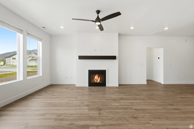 401 West 3085 South, Unit 329 Nibley, UT 84321 - Photo 12 of 34 Unfurnished living room with a glass covered fireplace, ceiling fan, light wood-style flooring, and recessed lighting