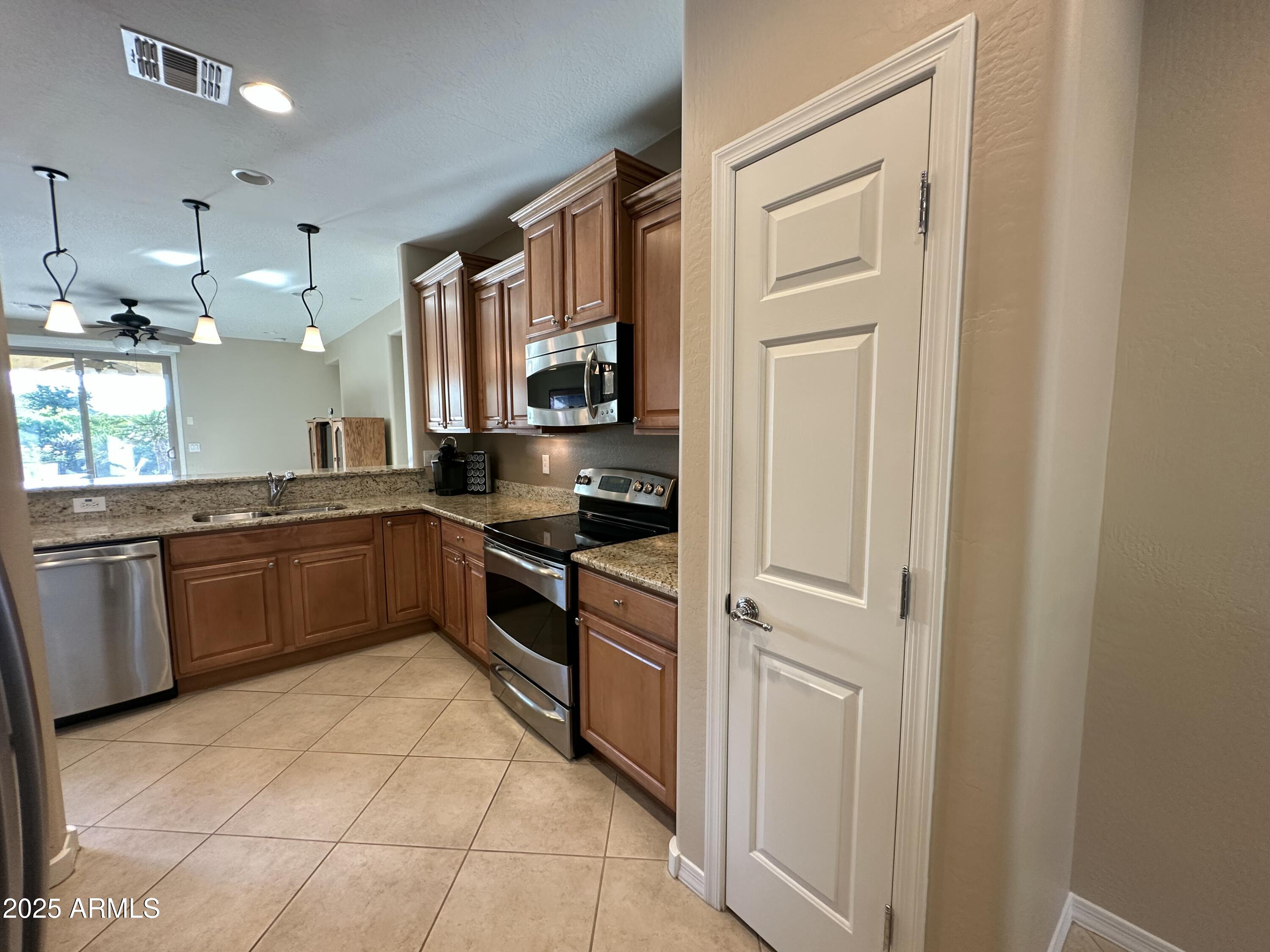 21280 North 262nd Drive Buckeye, AZ 85396 - Photo 13 of 51 a kitchen with stainless steel appliances granite countertop a refrigerator and a stove top oven