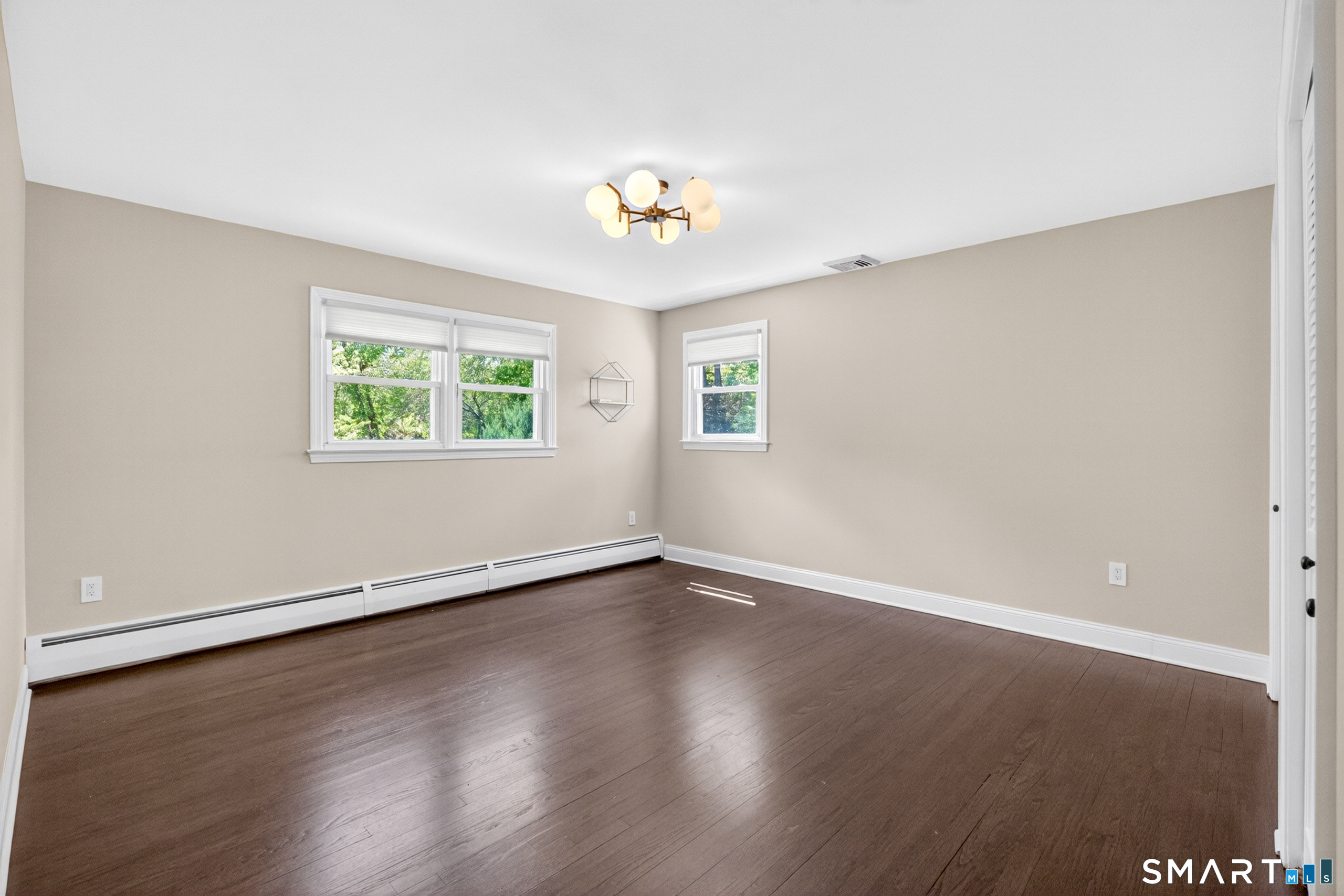 568 Wiese Road Cheshire, CT 06410 - Photo 21 of 40 an empty room with wooden floor chandelier fan and windows