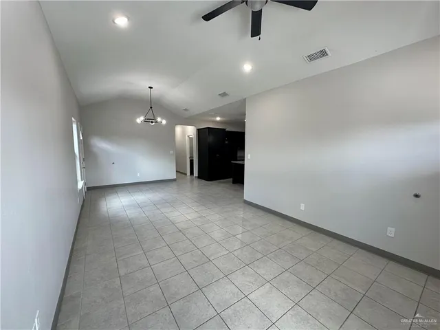 an empty room with kitchen and chandelier fan