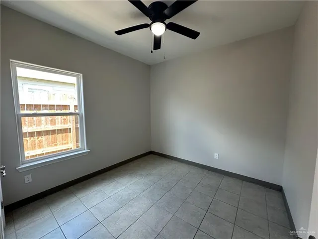 a view of an empty room with window and chandelier fan