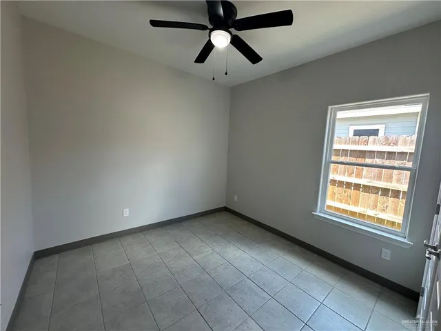 an empty room with chandelier fan and windows