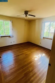 a view of empty room with window and wooden floor