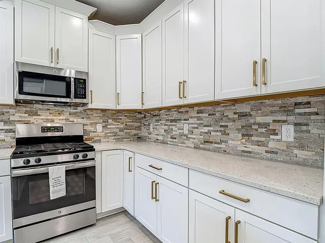 a kitchen with stainless steel appliances granite countertop white cabinets a stove a sink and dishwasher