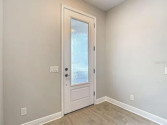 a view of an empty room with wooden floor and a ceiling fan