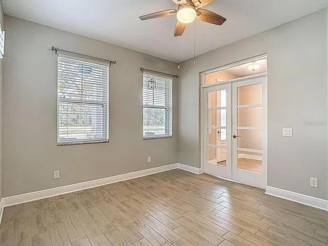 a view of an empty room with wooden floor and a window