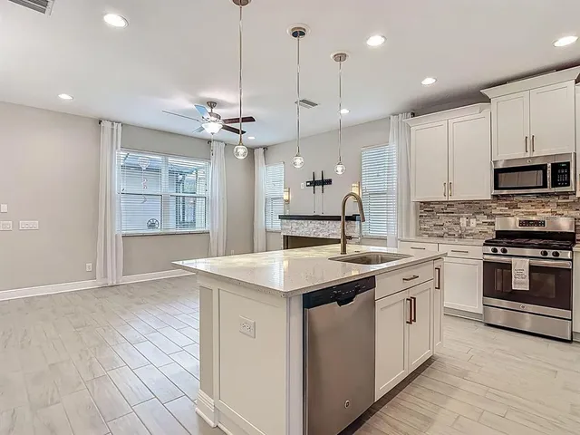 a kitchen with stainless steel appliances white cabinets a refrigerator and a stove top oven