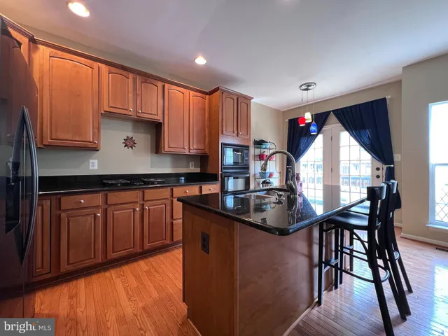 a kitchen with stainless steel appliances granite countertop wooden cabinets a stove a sink and a microwave