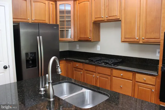 a kitchen with granite countertop a sink stainless steel appliances and cabinets