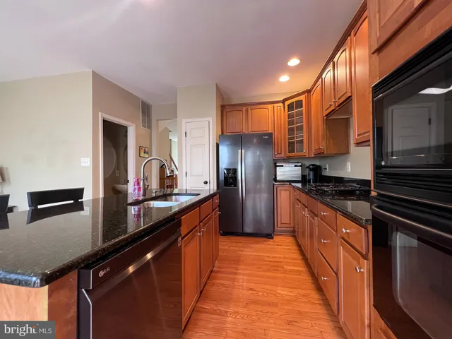 a kitchen with stainless steel appliances a sink dishwasher a refrigerator and cabinets with wooden floor