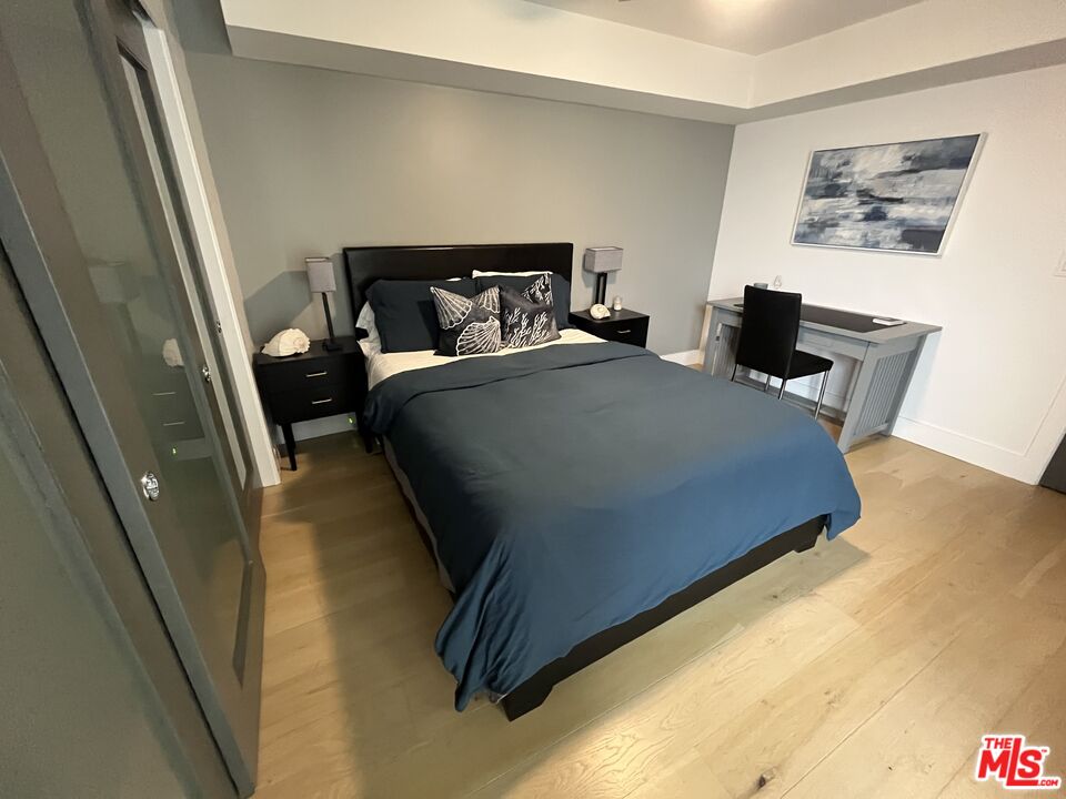 723 Palisades Beach Road, Unit 211 Santa Monica, CA 90402 - Photo 17 of 30 a bedroom with a bed and wooden floor