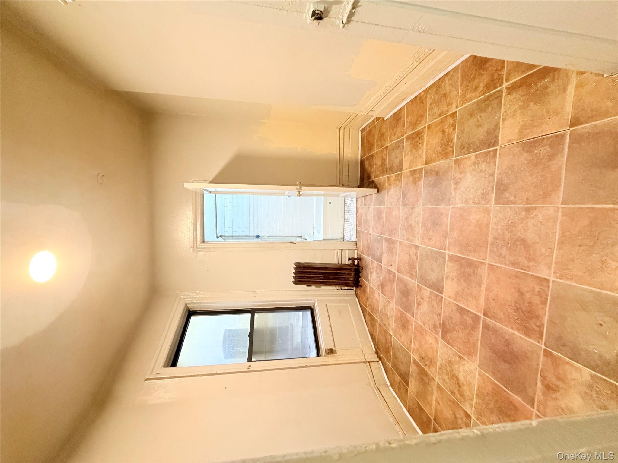 501 West 156th Street, Unit 22 Manhattan, NY 10032 - Photo 10 of 13 Tiled spare room with radiator heating unit and baseboards