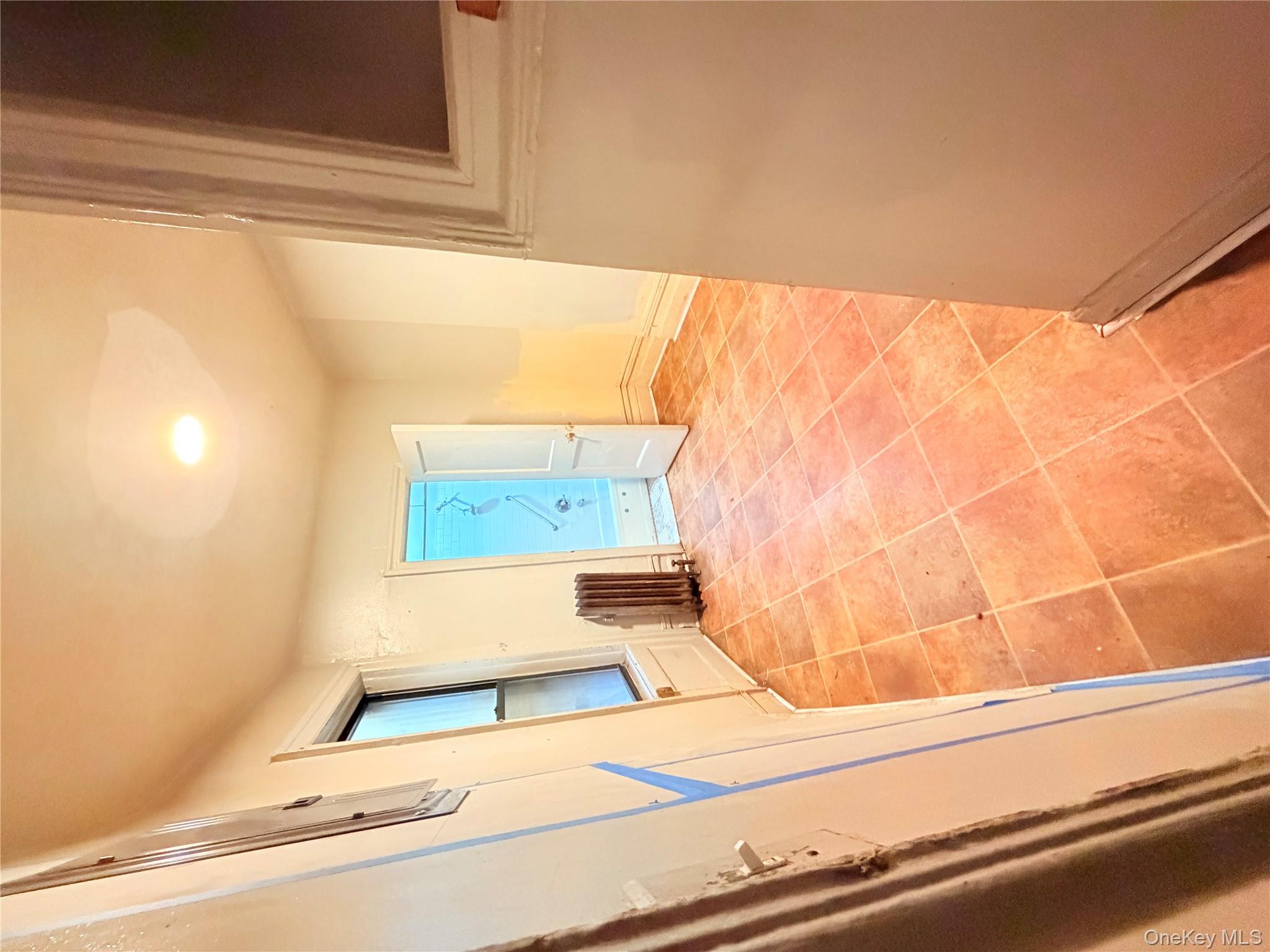 501 West 156th Street, Unit 22 Manhattan, NY 10032 - Photo 6 of 13 Hallway with light tile patterned flooring and radiator heating unit