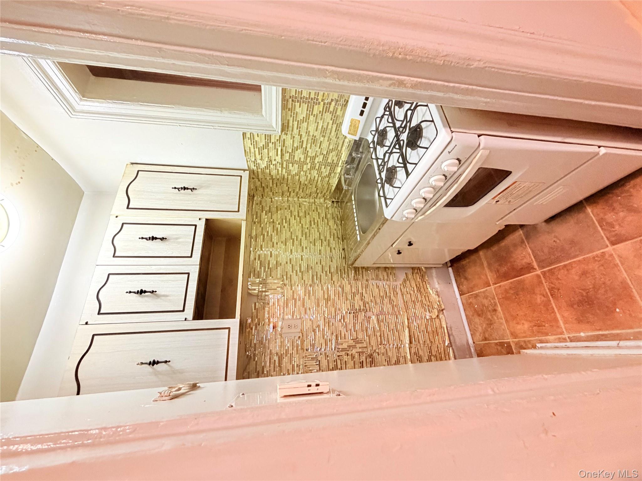 501 West 156th Street, Unit 22 Manhattan, NY 10032 - Photo 8 of 13 Kitchen with stove, light tile patterned floors, light countertops, and backsplash