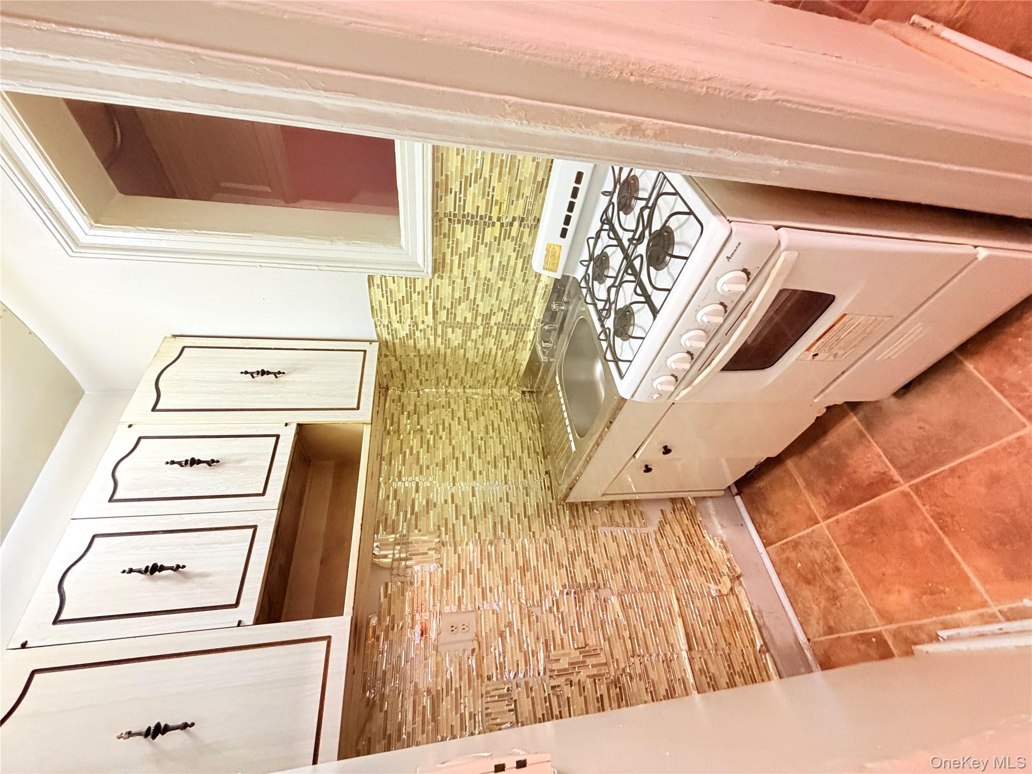 501 West 156th Street, Unit 22 Manhattan, NY 10032 - Photo 9 of 13 Kitchen with range, light tile patterned floors, light countertops, and backsplash