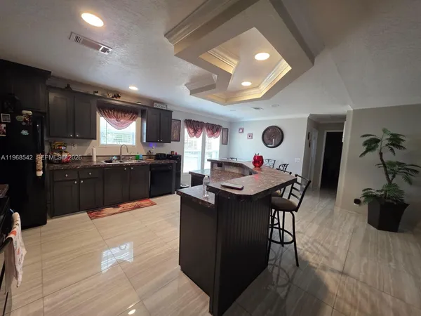 a kitchen with stainless steel appliances granite countertop a stove top oven a sink dishwasher and white cabinets with wooden floor