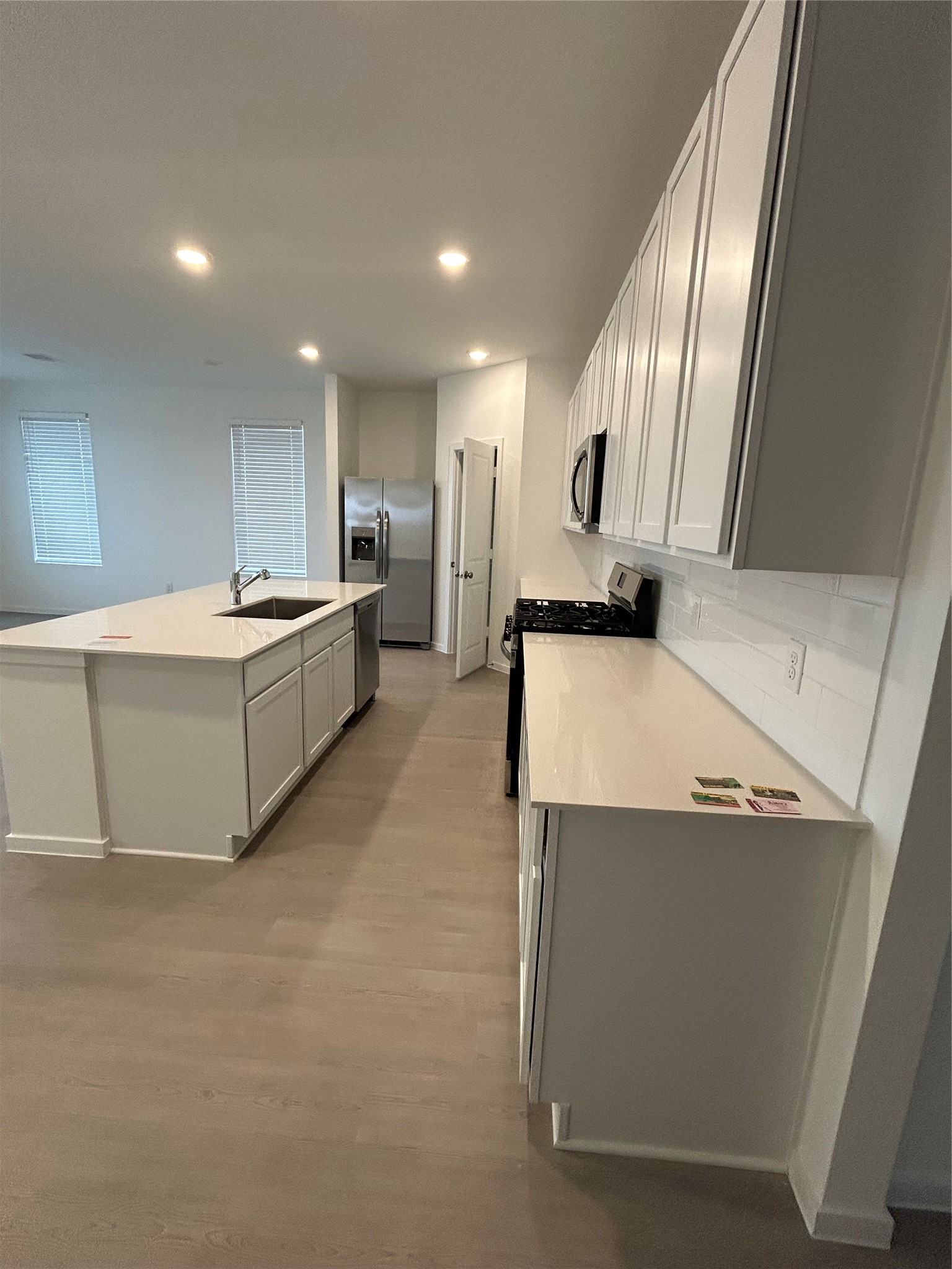 26419 Virginia Wild Rye Lane Katy, TX 77493 - Photo 10 of 31 Modern kitchen with white cabinetry and countertops, stainless steel appliances, and a spacious island. Bright, open layout with recessed lighting and light wood flooring.