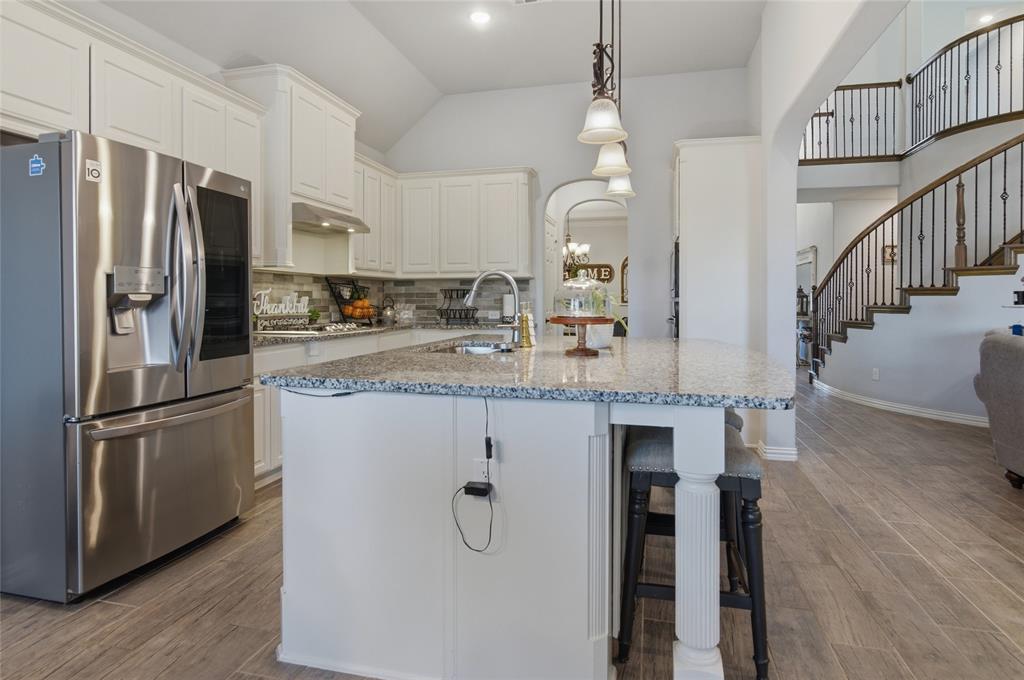 464 LeTara Ranch Drive Haslet, TX 76052 - Photo 11 of 37 Gourmet kitchen with white cabinetry, stainless steel appliances, a large island with integrated seating, and wood-finish flooring
