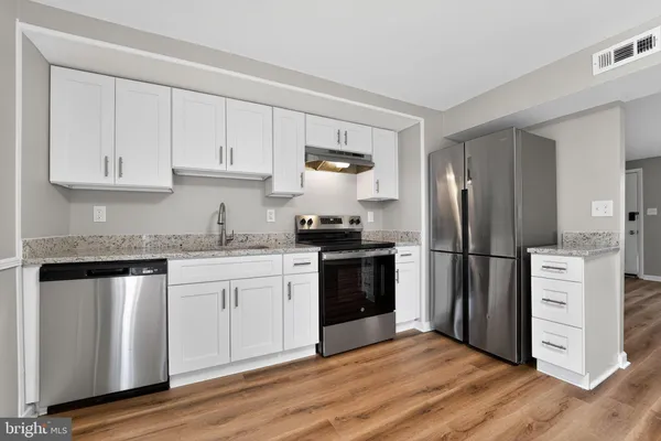 a kitchen with a refrigerator stove and white cabinets