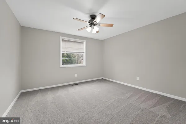 an empty room with a window and a ceiling fan