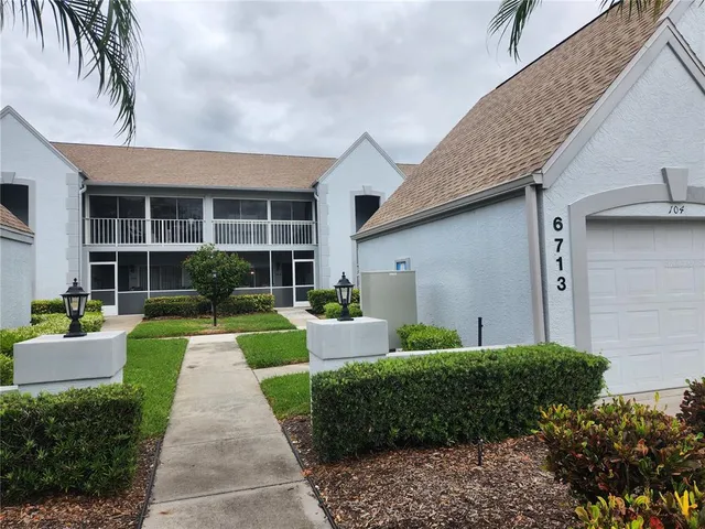 a front view of a house with a yard and potted plants